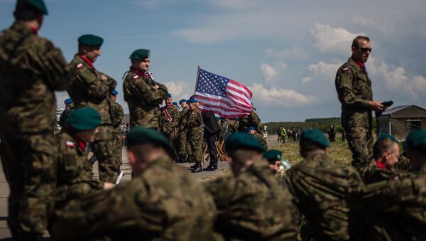 Soldados aguardam cerimônia de abertura da seção norte do escudo antimíssil em base militar na Polônia com bandeira dos EUA no plano de fundo - Sputnik Brasil