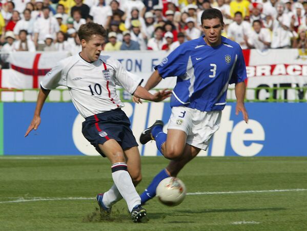 O atacante inglês Michael Owen chuta a bola para longe zagueiro brasileiro Lúcio durante a partida entre Inglaterra e Brasil nas quartas de final da Copa do Mundo de 2002. - Sputnik Brasil