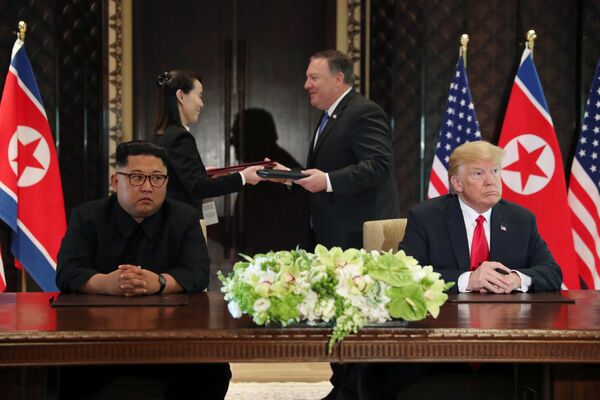 Líder norte-coreano, Kim Jong-un, e o presidente estadunidense, Donald Trump, assinam o documento conjunto após a cúpula histórica em Singapura, em 12 de junho de 2018 - Sputnik Brasil