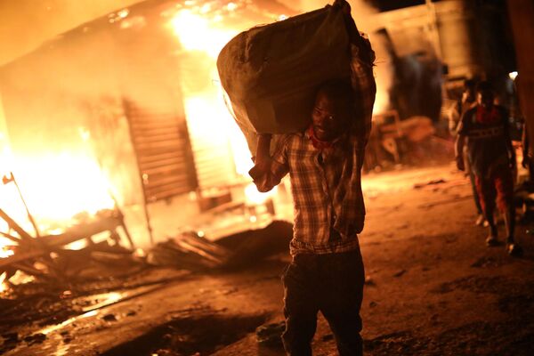 Um vendedor tenta salvar suas mercadorias durante o fogo em um mercado de Porto Príncipe, Haiti - Sputnik Brasil