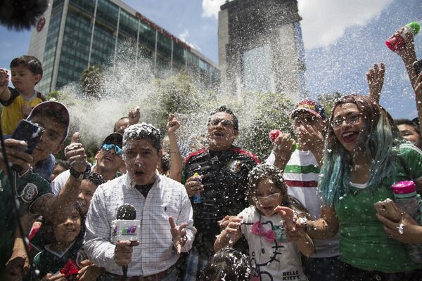 Um repórter e torcedores cobertos com espuma durante a celebração da vitória do México sobre a Alemanha durante a Copa do Mundo, a festa acontece em frente ao monumento Anjo da Independência, na cidade do México. - Sputnik Brasil