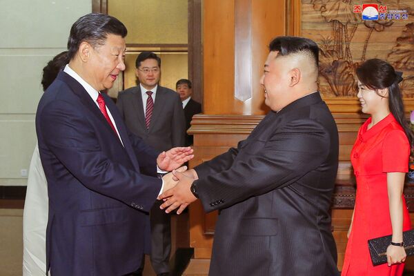 Os líderes da China, Xi Jinping, e da Coreia do Norte, Kim Jong-un, apertam as mãos durante seu encontro em Pequim em 19 de junho de 2018 - Sputnik Brasil