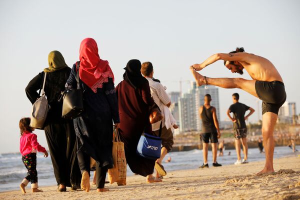 Pessoas curtindo a praia na costa do mar Mediterrâneo durante a celebração muçulmana de Eid al-Fitr, que marca o fim do jejum do Ramadã, Tel Aviv, Israel. - Sputnik Brasil