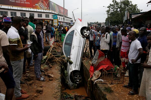 Pessoas observando um carro que caiu em um esgoto após uma inundação em Abidjan, Costa do Marfim. - Sputnik Brasil