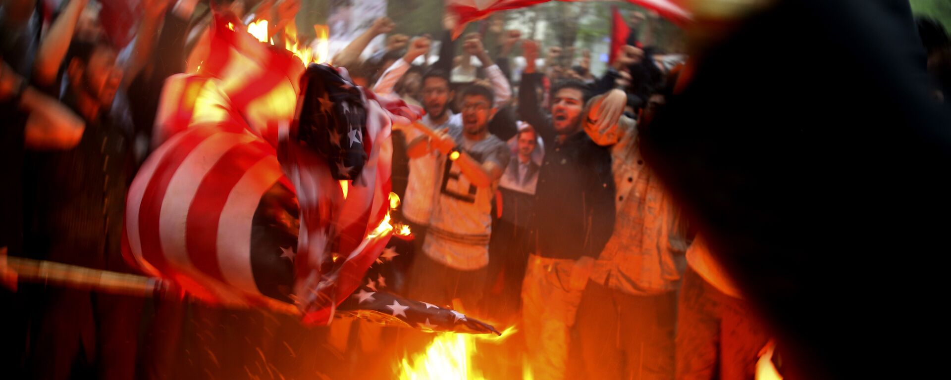 Manifestantes iranianos queimam bandeiras dos EUA durante protesto em frente a antiga embaixada dos Estados Unidos em resposta à decisão de Donald Trump, então presidente dos EUA, de desistir do acordo nuclear e renovar sanções a Teerã - Sputnik Brasil, 1920, 12.09.2022