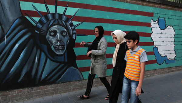 Uma família iraniana passa por pichações contrárias aos EUA na parede da antiga embaixada americana em Teerã. - Sputnik Brasil