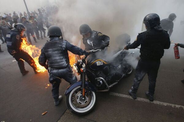Policiais extinguem fogo em moto incendiada durante uma manifestação contra o desaparecimento de estudantes em Ayotzinapa na Cidade do México em 26 de maio de 2015. - Sputnik Brasil