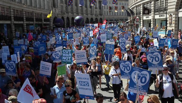 Em Londres, manifestantes seguram placas e faixas durante marcha em apoio ao NHS, o serciço nacional de saúde britânico. - Sputnik Brasil