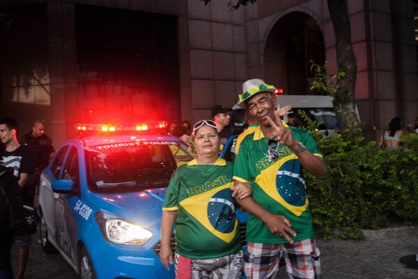 José Bispo de Oliveira posa ao lado da esposa em frente a uma viatura da Polícia Militar do Rio de Janeiro. Eles assistiram ao jogo do Brasil contra a Bélgica meio de uma multidão no Centro da cidade. - Sputnik Brasil