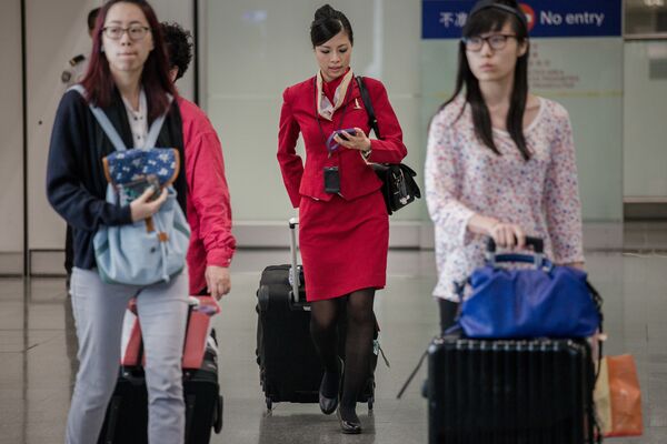 Aeromoça da companhia aérea de Cathay Pacific com sede em Hong Kong carregando sua bagagem - Sputnik Brasil