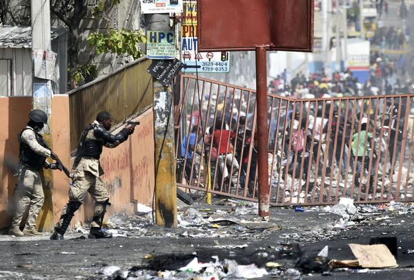 Policial haitiano aponta pistola à multidão durante os protestos contra o aumento dos preços dos combustíveis, nos arredores de Porto Príncipe - Sputnik Brasil