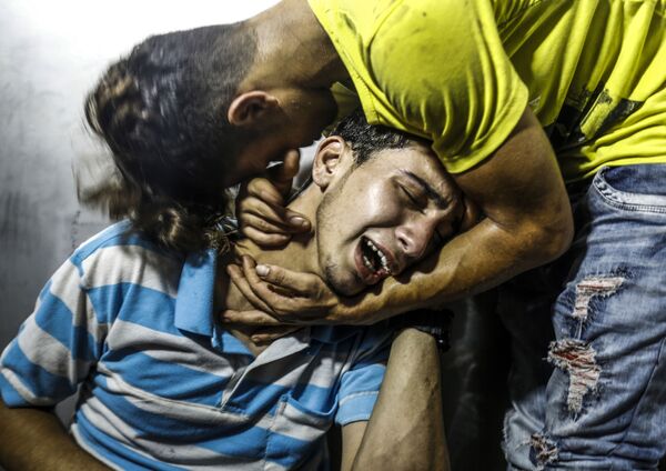 Palestinos chorando a morte de dois adolescentes mortos em um dos ataques aéreos de Israel à Faixa de Gaza. - Sputnik Brasil