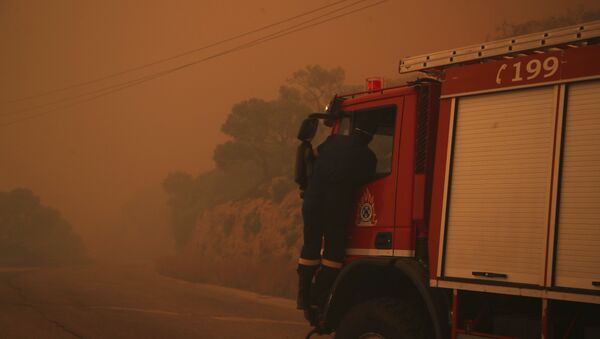 A fire truck is engulfed in a pall of orange smoke on a road near Kineta, west of Athens, Monday, July 23, 2018. - Sputnik Brasil