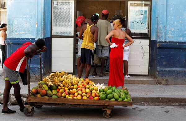 Homem puxando carrinho com frutas em frente de um mercado com a imagem de Raul Castro, Havana, Cuba. - Sputnik Brasil