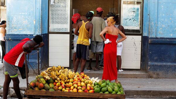 Homem puxando carrinho com frutas em frente de um mercado com a imagem de Raul Castro, Havana, Cuba. - Sputnik Brasil