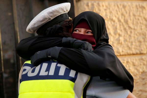 Mulher assustada abraça um policial durante uma manifestação contra a proibição do uso de niqab na rua, na Dinamarca - Sputnik Brasil