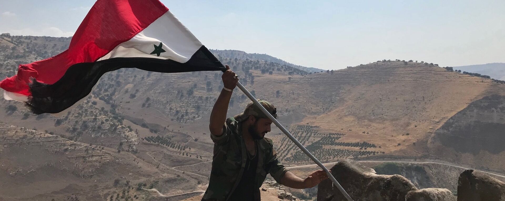 Militar sírio hasteia bandeira da Síria no sudoeste da província de Daraa, na fronteira com a Jordânia - Sputnik Brasil, 1920, 04.10.2021