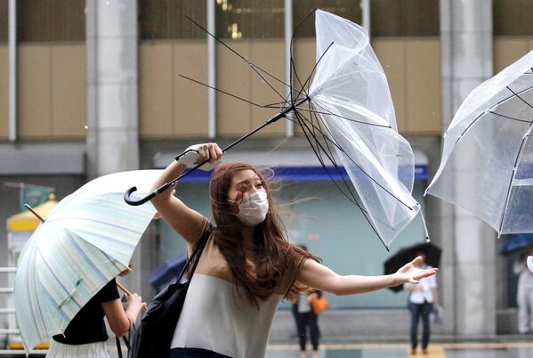 Moça tenta endireitar um guarda-chuva, em Tóquio - Sputnik Brasil