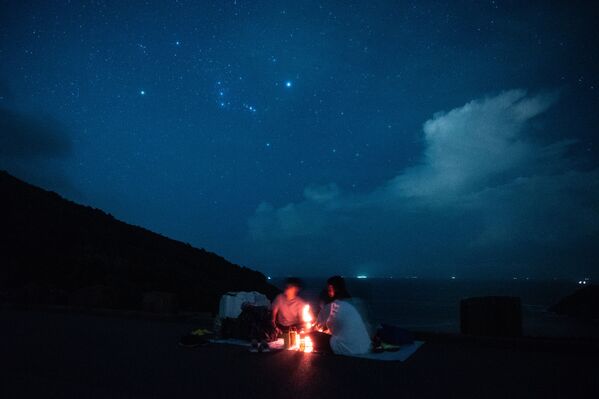 Pessoas observam o céu estrelado durante um piquenique na beira-mar em Hong Kong - Sputnik Brasil