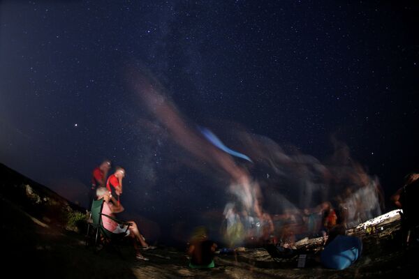 Pessoas observando a chuva de meteoros em praia rochosa de Malta - Sputnik Brasil