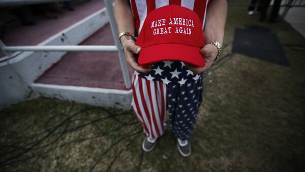 Um homem vestido com roupas de bandeira americana segura o boné Faça a América Grande Novamente. - Sputnik Brasil