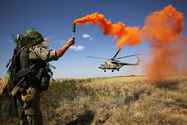 Militar russo participa das manobras táticas do Distrito Militar do Sul no polígono de Prudboi, na região de Volgogrado, junto a um helicóptero militar Mi-8 - Sputnik Brasil