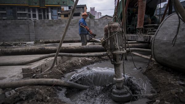 Homem coloca cimento dentro do carrinho de mão em uma área de construção civil, Xangai, China, 29 de novembro de 2016 (foto de arquivo) - Sputnik Brasil