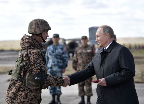 Presidente da Rússia Vladimir Putin apertando mão de um militar no polígono Tsugol - Sputnik Brasil