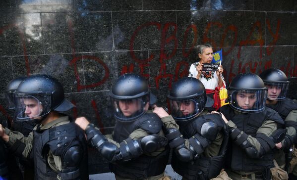 Mulher junto a agentes da polícia ucraniana em frente do Ministério Público da Ucrânia, em Kiev, durante um protesto de extrema-direita - Sputnik Brasil