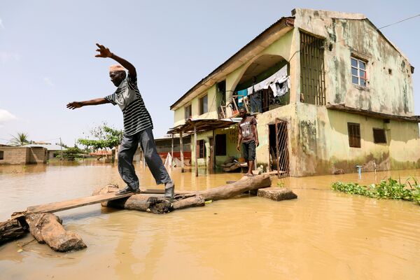 Habitante do estado nigeriano de Kogi anda pela rua em meio a uma inundação - Sputnik Brasil