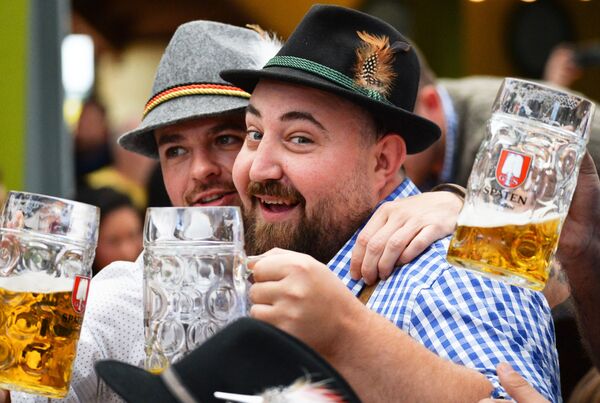 Visitantes seguram canecas com cerveja alemã durante a cerimônia de abertura do festival de cerveja Oktoberfest, em Munique, na Alemanha, em 22 de setembro de 2018 - Sputnik Brasil