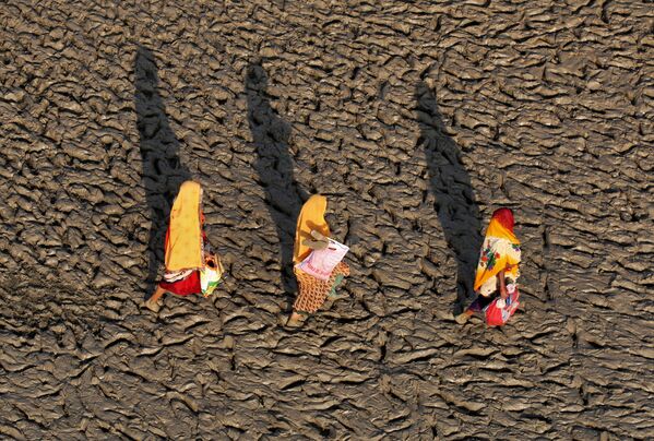 Mulheres caminhando pela margem do rio Ganges após terem realizado o mergulho sagrado, Índia. - Sputnik Brasil