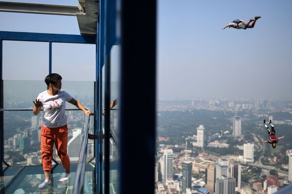 Turista observa paraquedistas pulando de um arranha-céu em Kuala Lumpur, na Malásia - Sputnik Brasil