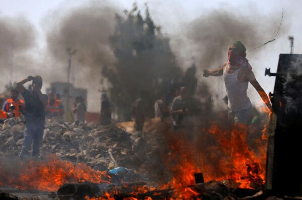Manifestantes palestinos jogam pedras aos militares israelenses durante protestos contra os planos de eliminar a aldeia beduína de Khan al-Ahmar perto de Ramallah, na Cisjordânia - Sputnik Brasil