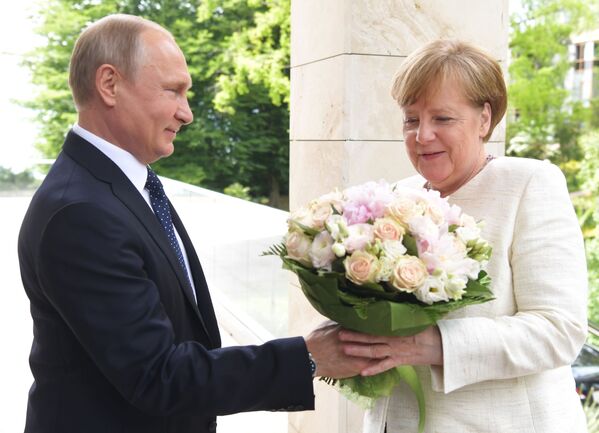 Vladimir Putin oferece um buquê de flores à chanceler da Alemanha, Angela Merkel, antes da reunião dos dois líderes em Sochi, na Rússia, 18 de maio de 2018 - Sputnik Brasil