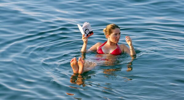 Moça lendo um livro enquanto relaxa na superfície d’água do mar Morto, Jordânia - Sputnik Brasil