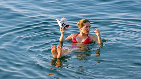 Moça lendo um livro enquanto relaxa na superfície d’água do mar Morto, Jordânia - Sputnik Brasil