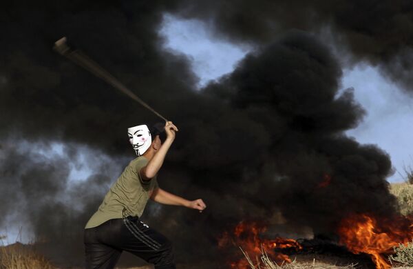 Manifestante usando máscara arremessa pedras contra as tropas israelenses perto da fronteira da Faixa de Gaza com Israel durante protesto, 29 de outubro de 2018 - Sputnik Brasil