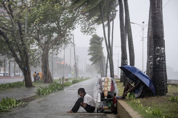 Vendedora de rua sentada no chão durante tufão Yutu nas Filipinas, em 30 de outubro de 2018 - Sputnik Brasil
