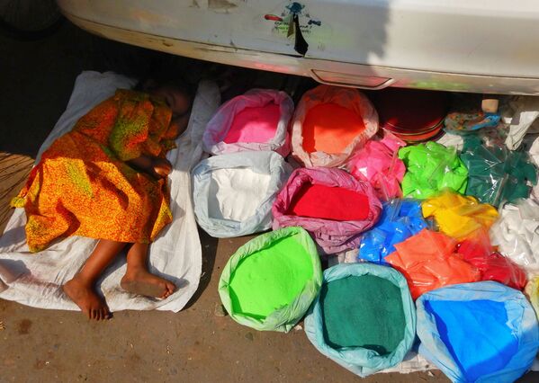 Criança dorme perto de sacos com pó colorido em um mercado em Nova Deli, na Índia - Sputnik Brasil
