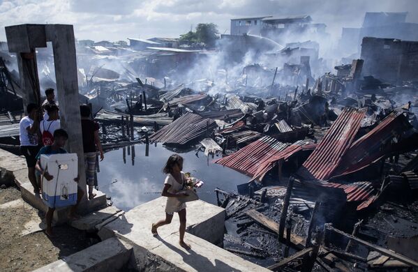 Menina passa pelas moradias destruídas pelo fogo em uma favela de Navotas, na Baía de Manila, nas Filipinas - Sputnik Brasil