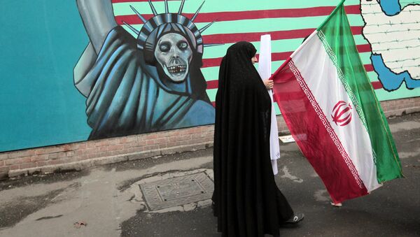 Mulher iraniana segura bandeira nacional enquanto passa por um muro representando a Estátua da Liberdade na parede da antiga embaixada dos EUA em Teerã (foto de arquivo) - Sputnik Brasil