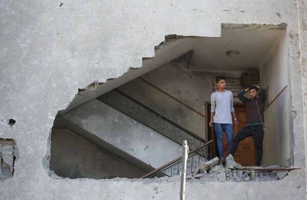 Moços palestinos em um prédio residencial semi-destruído por um ataque aéreo israelense na Faixa de Gaza - Sputnik Brasil