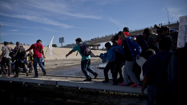 Migrants cross the river at the Mexico-U.S. border after getting past a line of Mexican police at the Chaparral crossing in Tijuana, Mexico, Sunday, Nov. 25, 2018 - Sputnik Brasil
