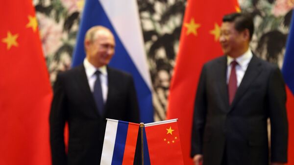 The Russian and Chinese national flags are seen on the table as Russia's President Vladimir Putin (back L) and his China's President Xi Jinping (back R) stand during a signing ceremony at the Diaoyutai State Guesthouse in Beijing on November 9, 2014. - Sputnik Brasil