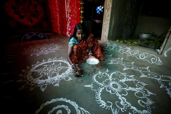 Purnima Shaw, de 27 anos, cria um desenho ritual de pasta de arroz no chão de barro por ocasião do festival Laxmi Puja. - Sputnik Brasil