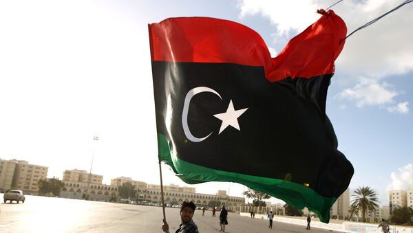 Líbio agita bandeira nacional enquanto manifestantes se reúnem para protesto contra a munição do Exército líbio, na cidade de Benghazi, em 27 de fevereiro de 2015 - Sputnik Brasil