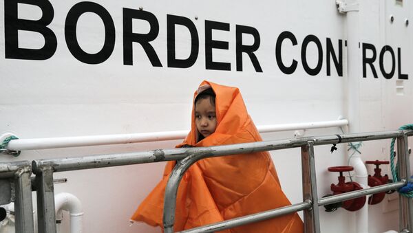 Uma menina refugiada, coberta com um cobertor e resgatada em alto mar, prepara-se para desembarcar um navio-patrulha da Frontex no porto de Mitilene, na ilha de Lesbos, na Grécia (arquivo) - Sputnik Brasil
