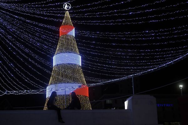 Duas garotas sentadas em torno de uma árvore de Natal na Praça Salvador do Mundo, em El Salvador. - Sputnik Brasil