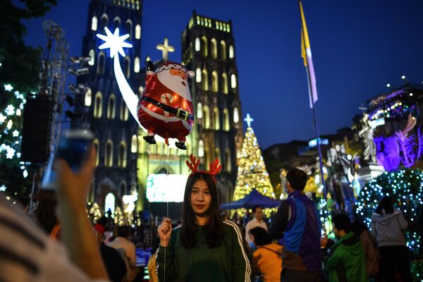 Vietnamita posa com balão de Papai Noel perto de catedral na cidade de Hanói, Vietnã, em 24 de dezembro de 2018 - Sputnik Brasil
